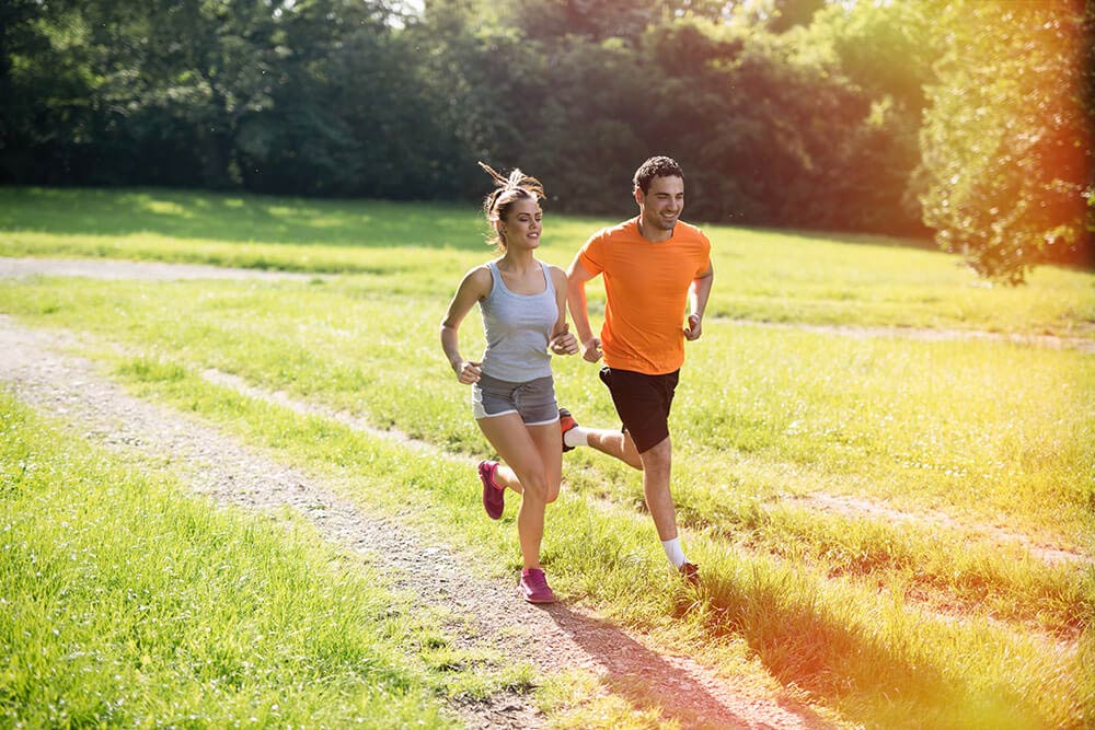 Una coppia si allena facendo running in un sentiero tra la natura
